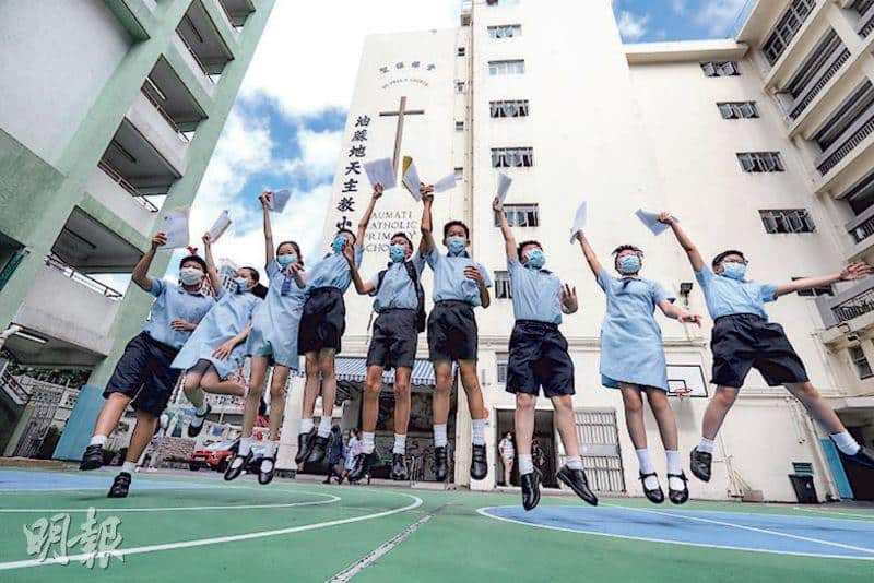 在油蔴地天主教小學，有學生昨獲知派位結果後心情興奮，手持通知書在操場跳起。有家長則稱今晚會吃自助餐慶祝。（李紹昌攝）